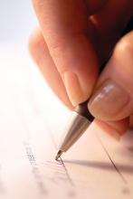 Up close of a person signing a contract.